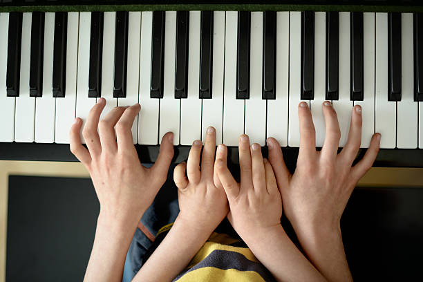 istock Two children's hands on  piano- 1 467646952