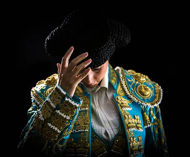 Woman bullfighter salutes with his montera in black background