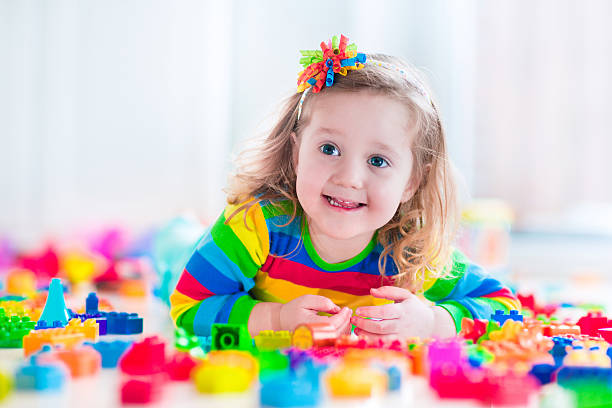 istock Happy little girl playing with toy blocks 467648372