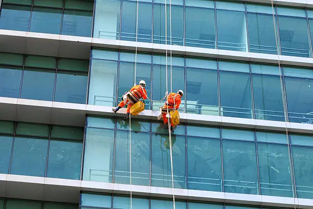 Photo of Workers clean the glass on tall buildings