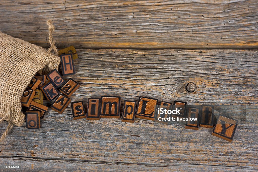 vintage letterpress and burlap bag Vintage letterpress spelling simplicity spilling out of a burlap bag on rustic barn wood. 2015 Stock Photo