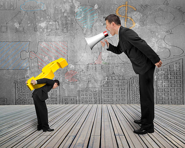 istock Boss using megaphone shouting at employee carrying gold dollar s 467671796