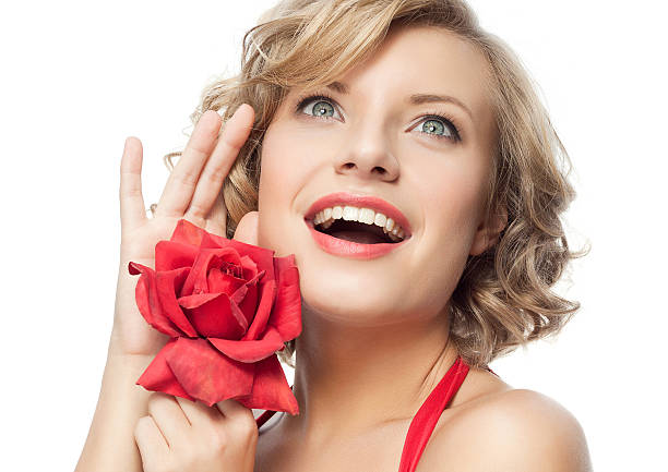 Smiling Latin woman enjoying the sunlight in a park with red gerbera flowers in her shirt