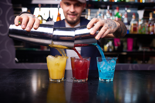 Bartender adding multi-colored syrups into cocktails