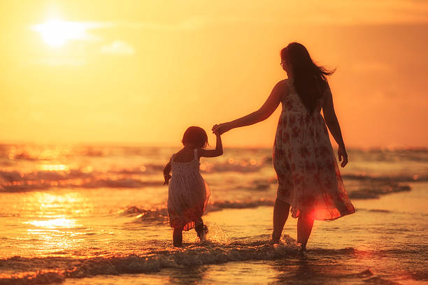 Mother with her daughter on the beach stock photo