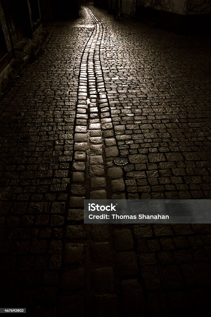 Cobble Stone Street at Night A dark cobble stone street light by a lone light source. Black And White Stock Photo