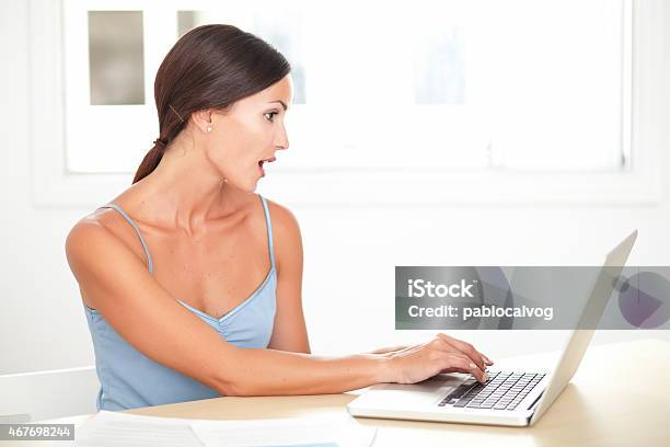 Pretty Young Woman Looking Shocked While Studying Stock Photo - Download Image Now - 2015, 30-34 Years, 30-39 Years