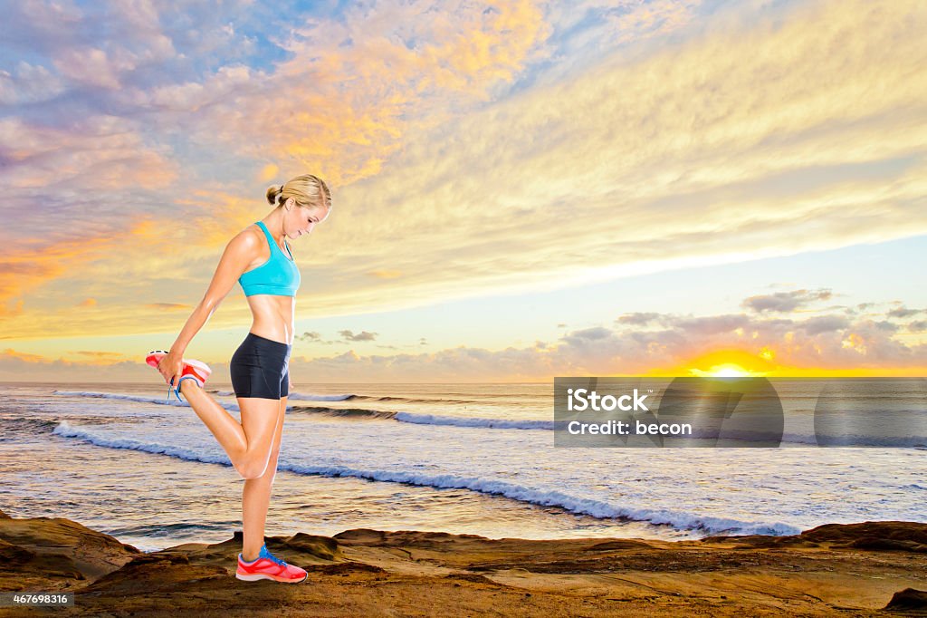 Fit Woman Stretching at Sunset Fit Woman stretching her thigh at sunset. Sunset Cliffs, California. Blonde female is holding her ankle and stretching her quadricep. 2015 Stock Photo