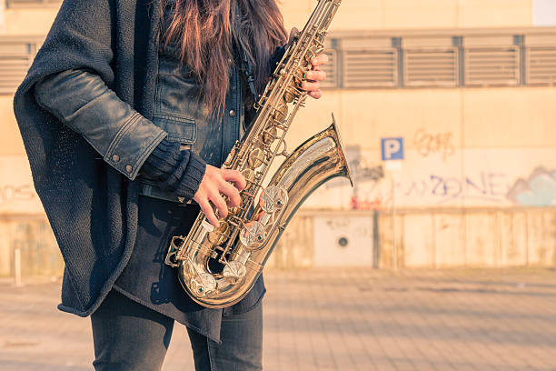 istock Beautiful young woman playing tenor saxophone 467702976