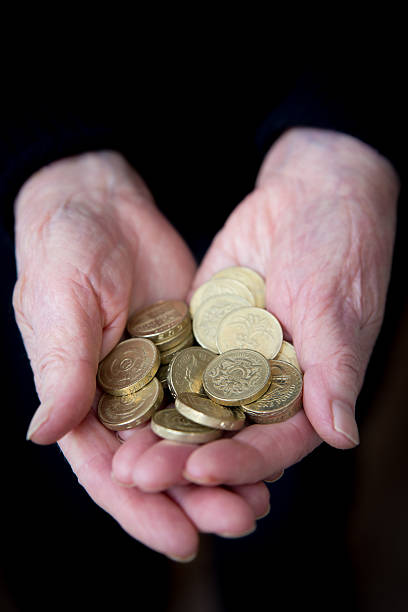 anziani mani con monete sterlina britannica - one pound coin british coin old uk foto e immagini stock