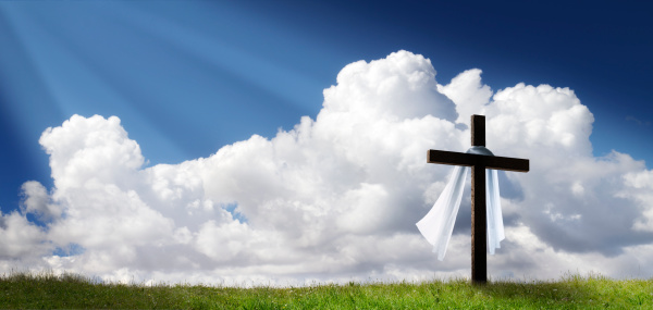 This dramatic Easter Morning Sunrise panorama with blue sky, sunbeams, and large cross on a grass covered hill makes a great banner cover for print or web.