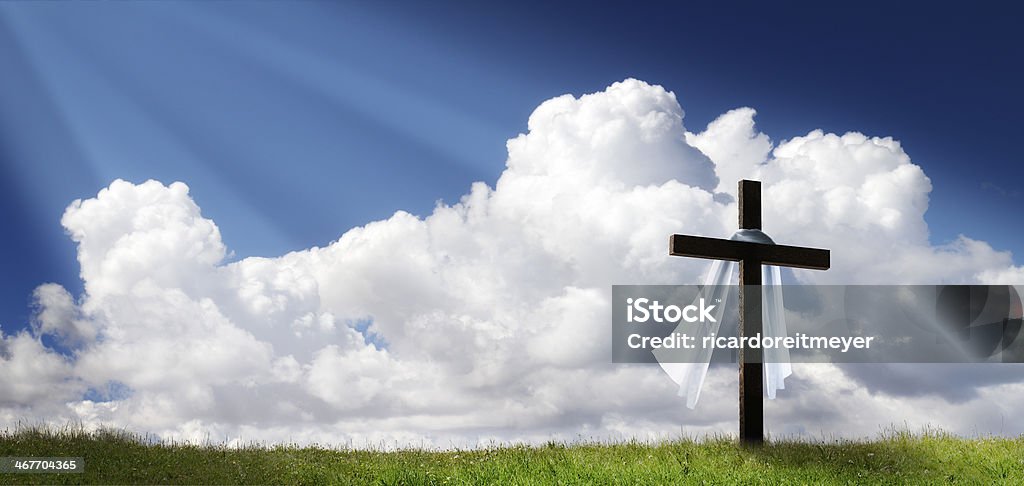 Dramatic Panorama Easter Sunday Morning Sunrise With Cross On Hill This dramatic Easter Morning Sunrise panorama with blue sky, sunbeams, and large cross on a grass covered hill makes a great banner cover for print or web. Easter Stock Photo