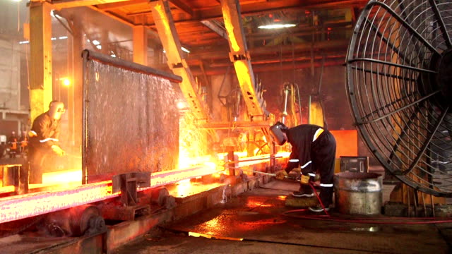 Workers cutting fiery steel blocks
