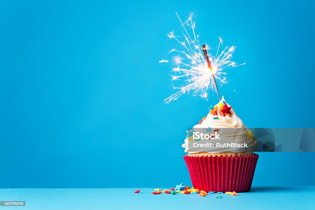 Cupcake with sparkler on blue Cupcake with sparkler against a blue background Cupcake Stock Photo
