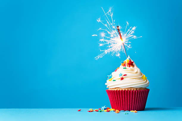 Cupcake with sparkler on blue Cupcake with sparkler against a blue background cupcake stock pictures, royalty-free photos & images