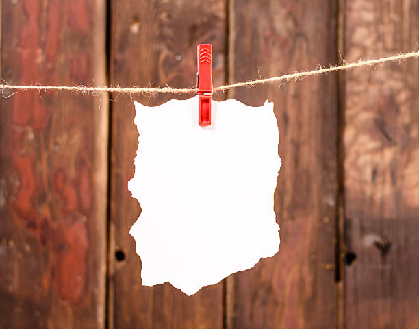 White empty paper note hanging on clothesline, Old wood background. stock photo