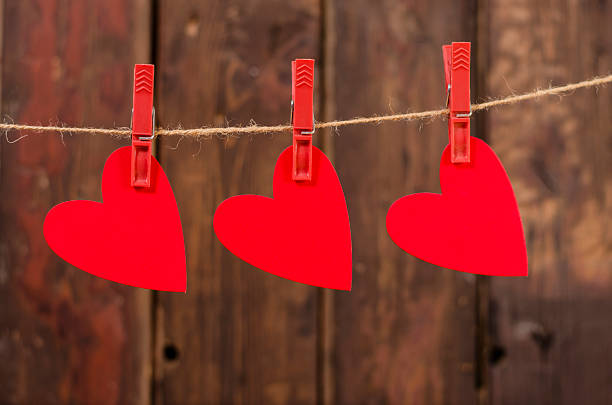 istock Three red hearts hanging on the clothesline. Old wood background. 467705763