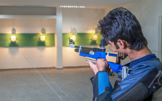 Young Indian aiming at the target with an air rifle