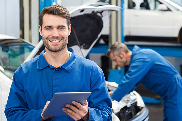 uśmiechająca się mechanik za pomocą tabletu - auto repair shop adult auto mechanic blue zdjęcia i obrazy z banku zdjęć