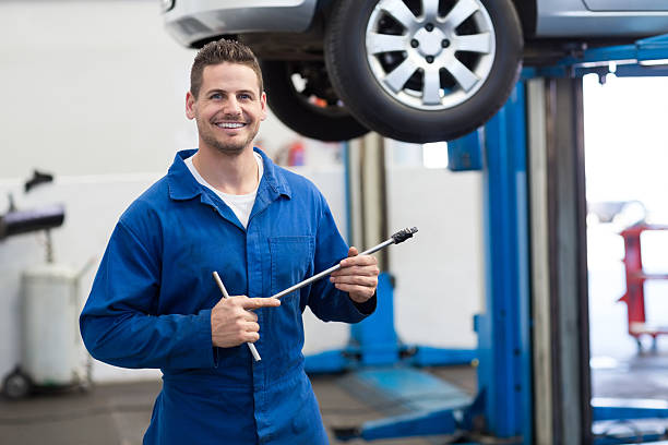 istock Mechanic smiling at the camera holding tool 467712600
