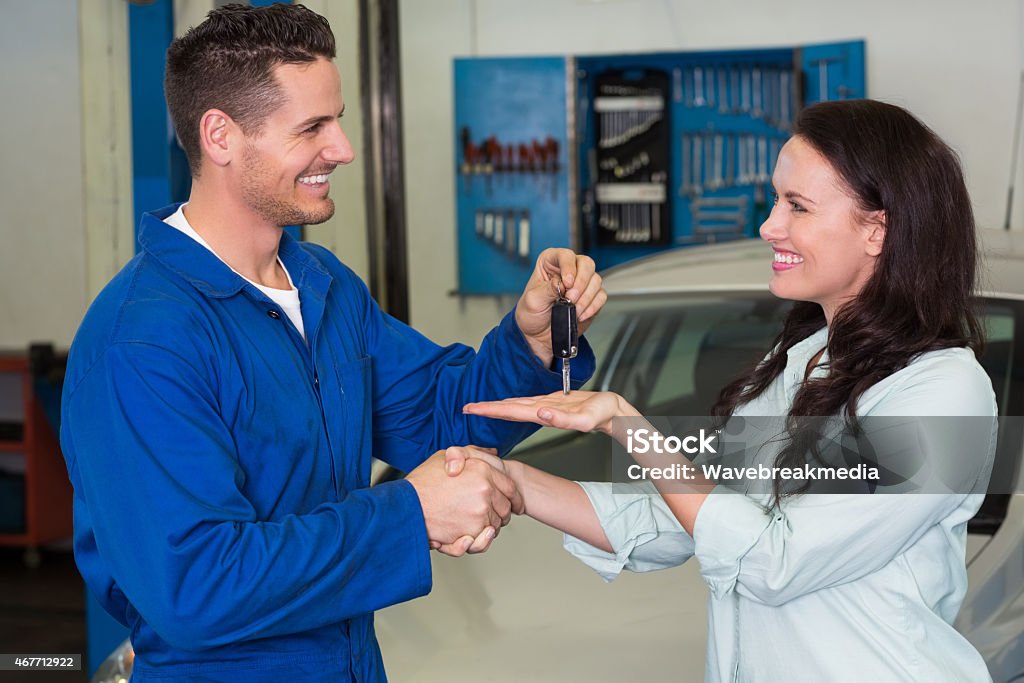 Mechanic giving keys to satisfied customer Mechanic giving keys to satisfied customer at the repair garage 20-29 Years Stock Photo