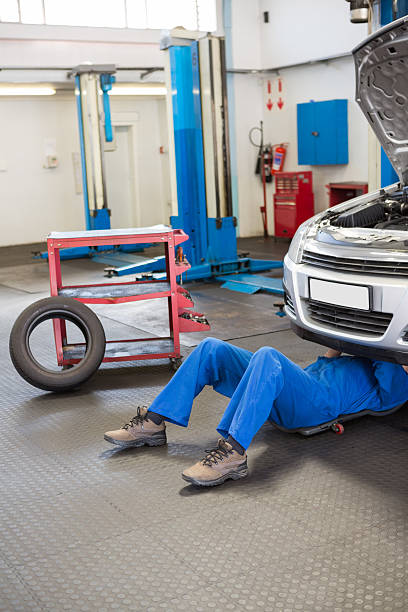 istock Mechanic lying and working under car 467713754