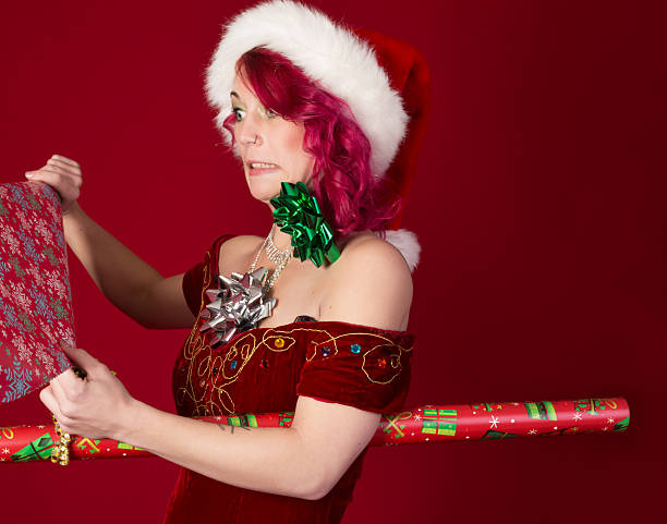 istock Pink-haired Santa's elf fighting with wrapping paper. 467714195