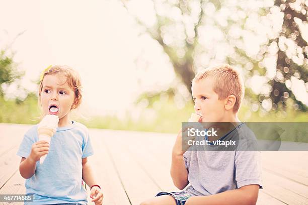 Boy And Girl Outdoors Eating Ice Cream On Bokeh Background Stock Photo - Download Image Now