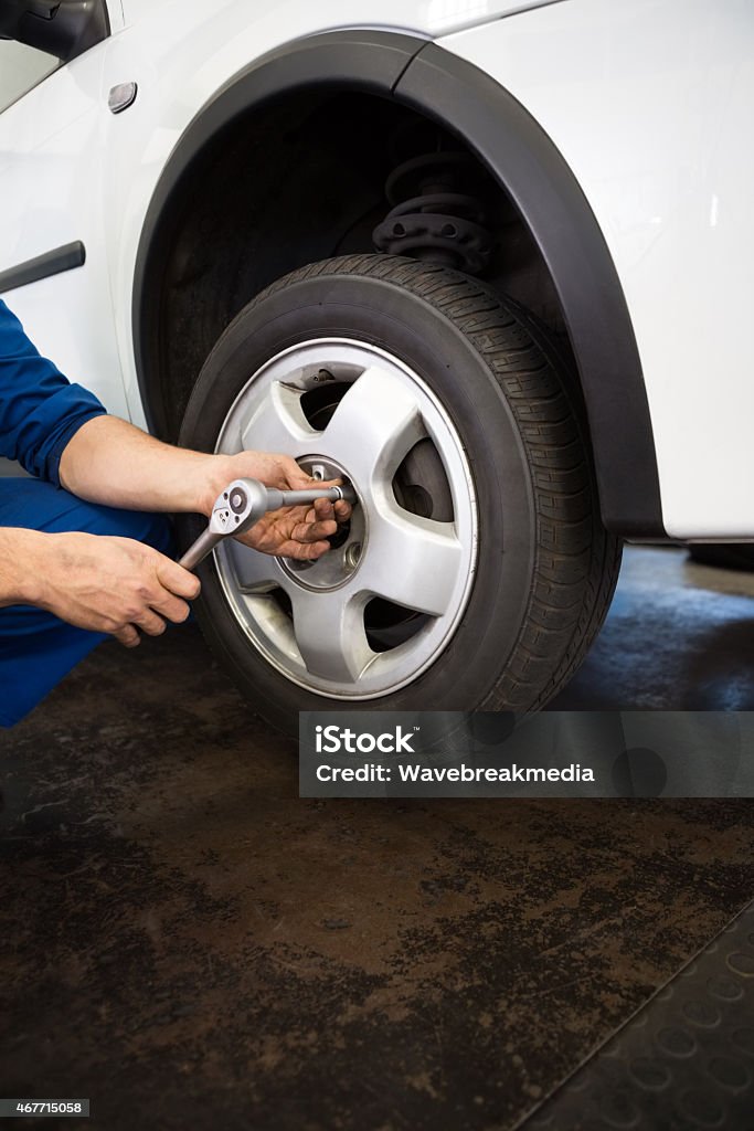 Mechanic adjusting the tire wheel Mechanic adjusting the tire wheel at the repair garage 2015 Stock Photo