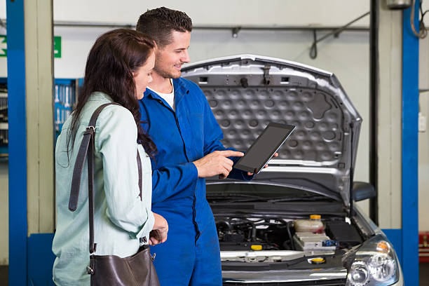 Mechanic explaining issues to customer after car service Mechanic showing customer the problem with car at the repair garage auto repair shop mechanic digital tablet customer stock pictures, royalty-free photos & images