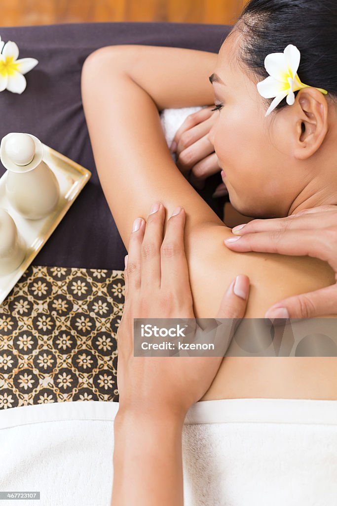 Indonesian woman getting a massage Masseur giving Indonesian Asian woman a aroma therapy massage with essential oil in a beauty wellness spaIndonesian Asian woman in wellness beauty day spa having aroma therapy massage with essential oil, looking relaxed Adult Stock Photo