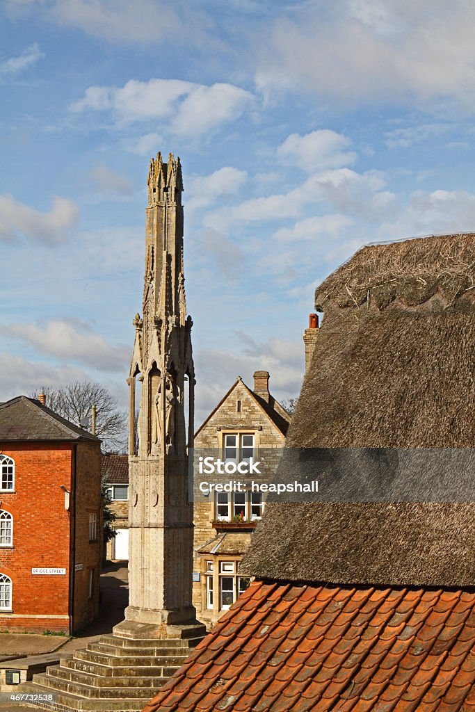 The Eleanor cross in Geddington. The Eleanor crosses were a series of twelve decorated stone monuments topped with tall crosses, erected by King Edward I in memory of his wife, Eleanor of Castile. The location of the crosses marked the nightly resting-places along the route taken when her body was transported to London. 2015 Stock Photo