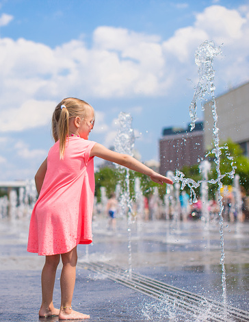 Adorable little girl playing in street fountain