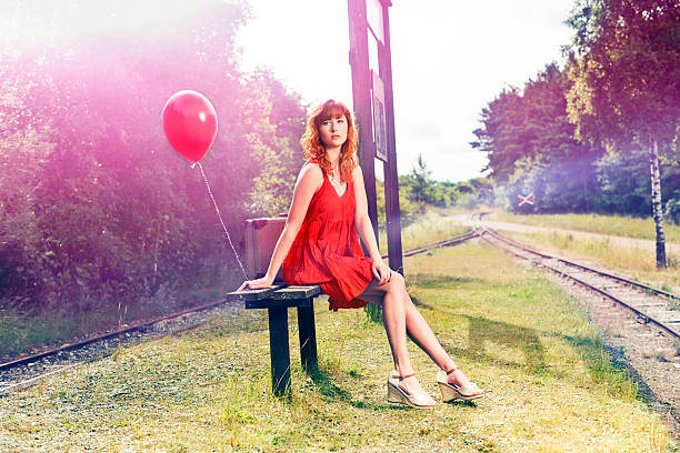 girl with pigtails walk on rails with a balloon on a string in her hand