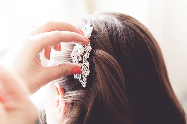 A hand placing a head piece onto a bride's hair
