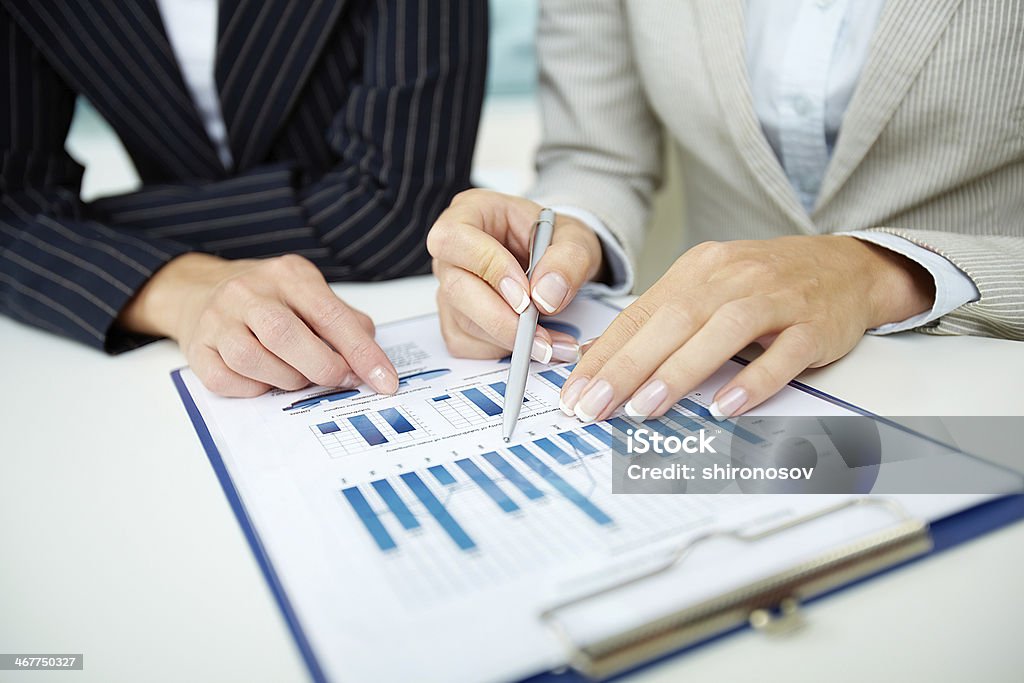 Businesswoman going through stock reports Image of female hands with pens over business document at meeting Ballpoint Pen Stock Photo