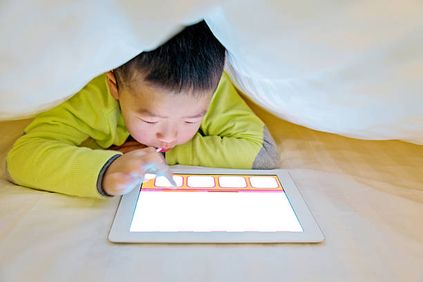 istock Little boy watching digital tablet in bed 467751280