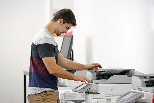 One young adult male using a high tech photocopier in a library