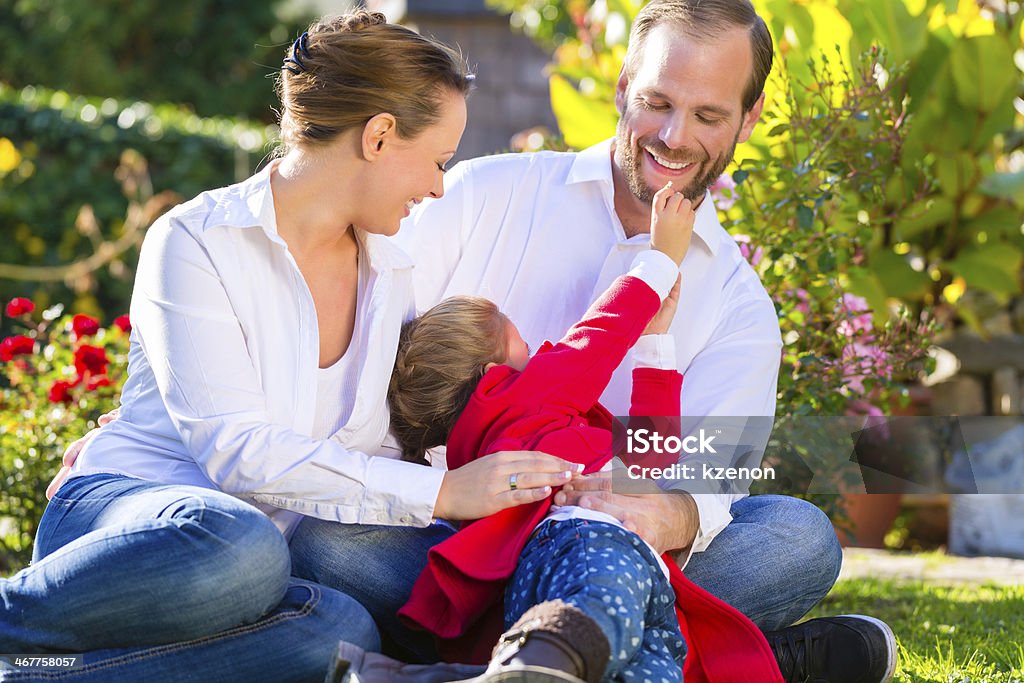 Family on the garden lawn Family with mother, father and daughter together in the garden meadowFamily with mother, father and daughter together in the garden meadow Activity Stock Photo