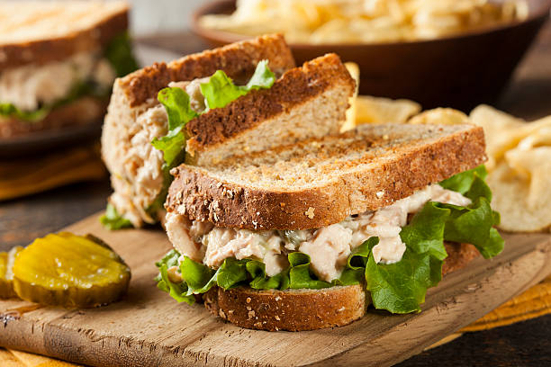 Tuna sandwich with lettuce on wheat toast Healthy Tuna Sandwich with Lettuce and a Side of Chips TUNA SANDWICH stock pictures, royalty-free photos & images
