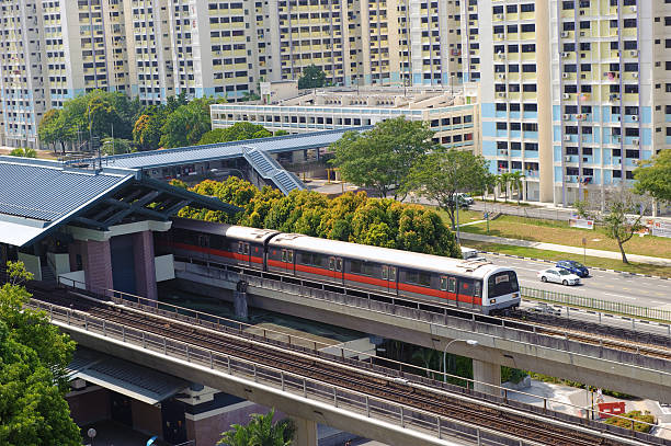 Singapore MRT train station Singapore, Singapore - Jan 29, 2014 : Singapore MRT train passing into a station along a road in a new neighbourhood town taken in the day on Jan 29, 2014 singapore mrt stock pictures, royalty-free photos & images