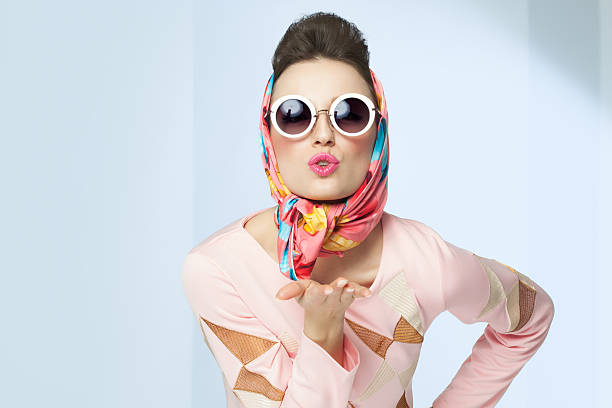 Sixties Style Girl Sixties style girl blowing a kiss. Retro fashion with silk scarf and sunglasses. retro fashion stock pictures, royalty-free photos & images