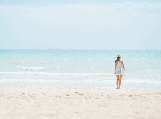 istock young woman standing on beach. rear view 467768965