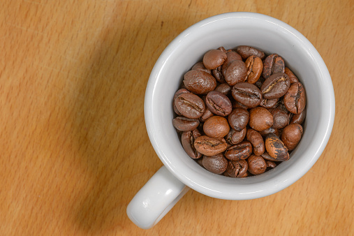 Nice cup of coffe with toasted coffee seeds inside on wood background