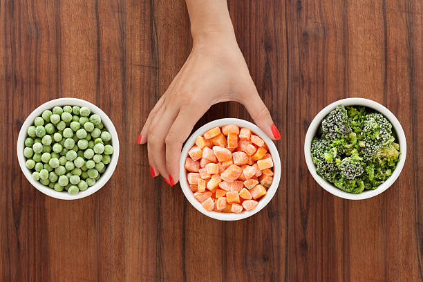 Selecting frozen vegetables Three bowls with varieties of frozen vegetables and woman's hand holding the middle one PEAS stock pictures, royalty-free photos & images