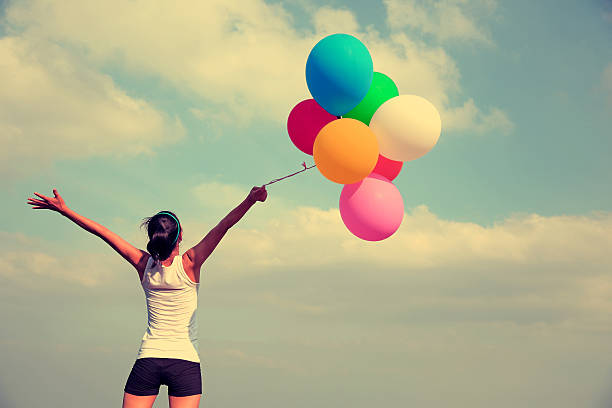 istock cheering woman with colorful balloons 467778654