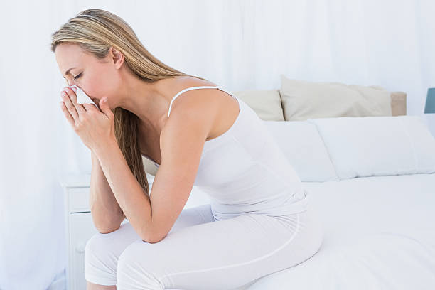 istock Sick blonde blowing her nose on tissue 467786936