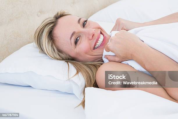 Happy Woman Lying In Bed Under Duvet Stock Photo - Download Image Now - 2015, 30-39 Years, 35-39 Years