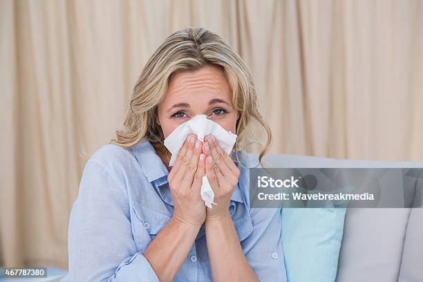 Sick Blonde On Couch Sneezing Stock Photo - Download Image Now - 2015, 30-39 Years, 35-39 Years