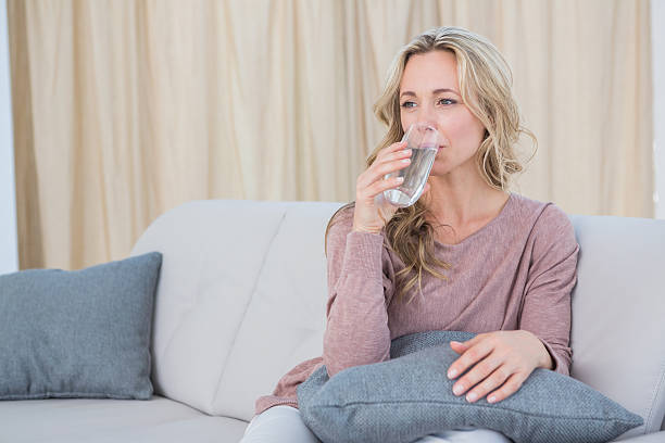 istock Pretty blonde sitting on couch drinking water 467787604
